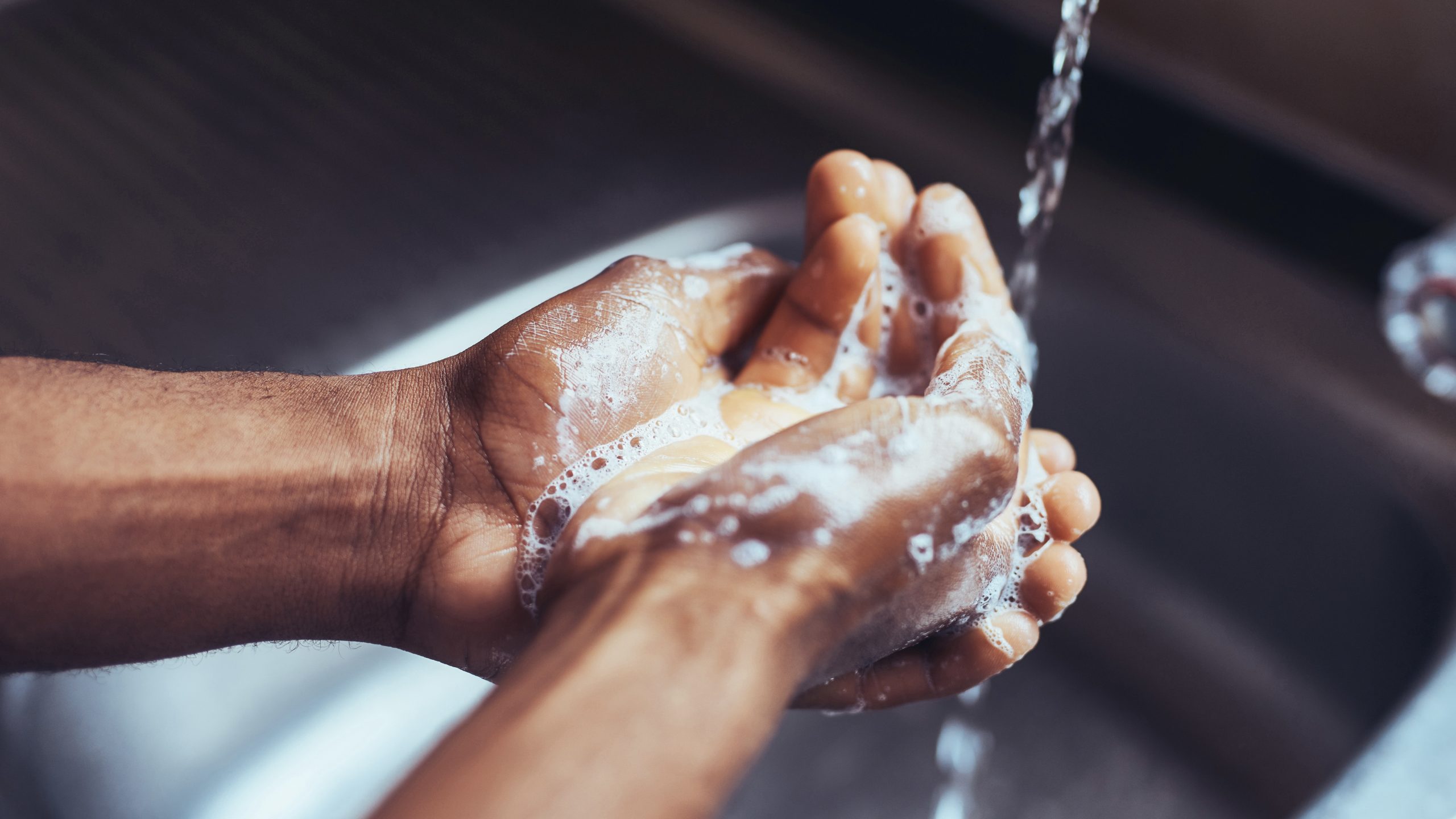 Closeup of soapy hands under water streaming from a faucet