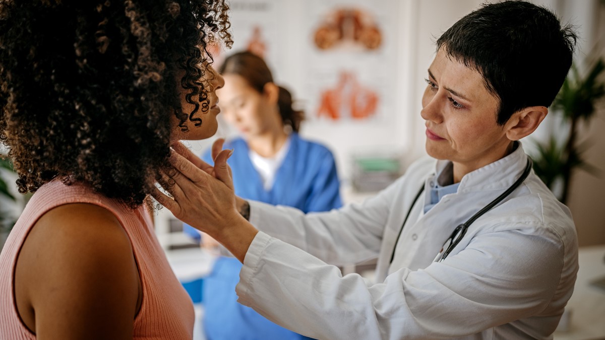 A female healthcare specialist examines a female patient in a clinic.