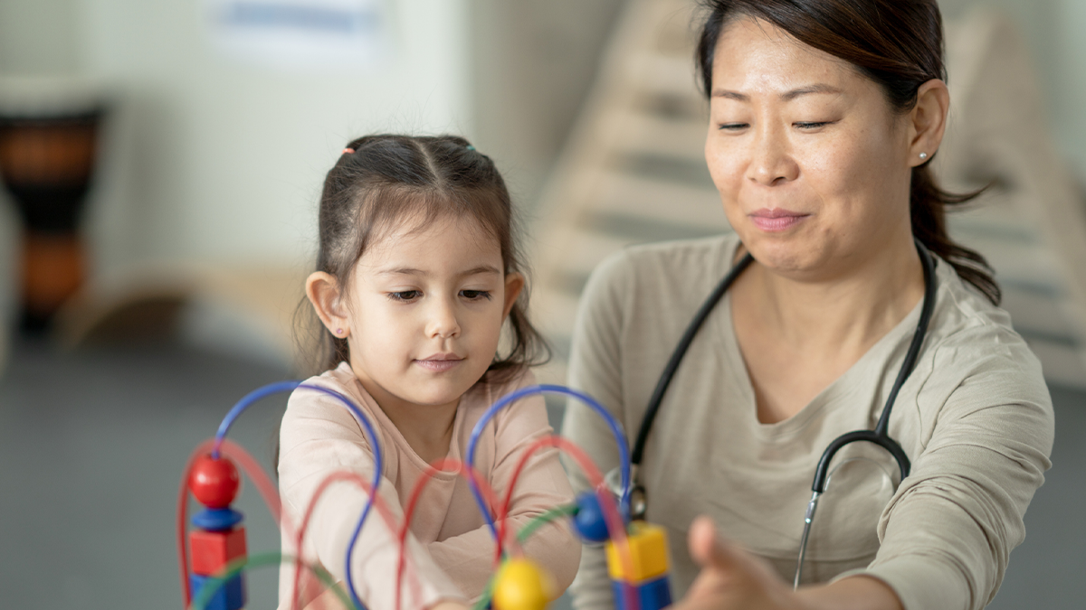A doctor watching child play as part of developmental monitoring.