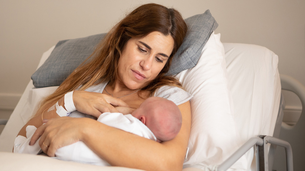 mPINC FAQ breastfeeding mom A newborn baby with their mom in a hospital bed.