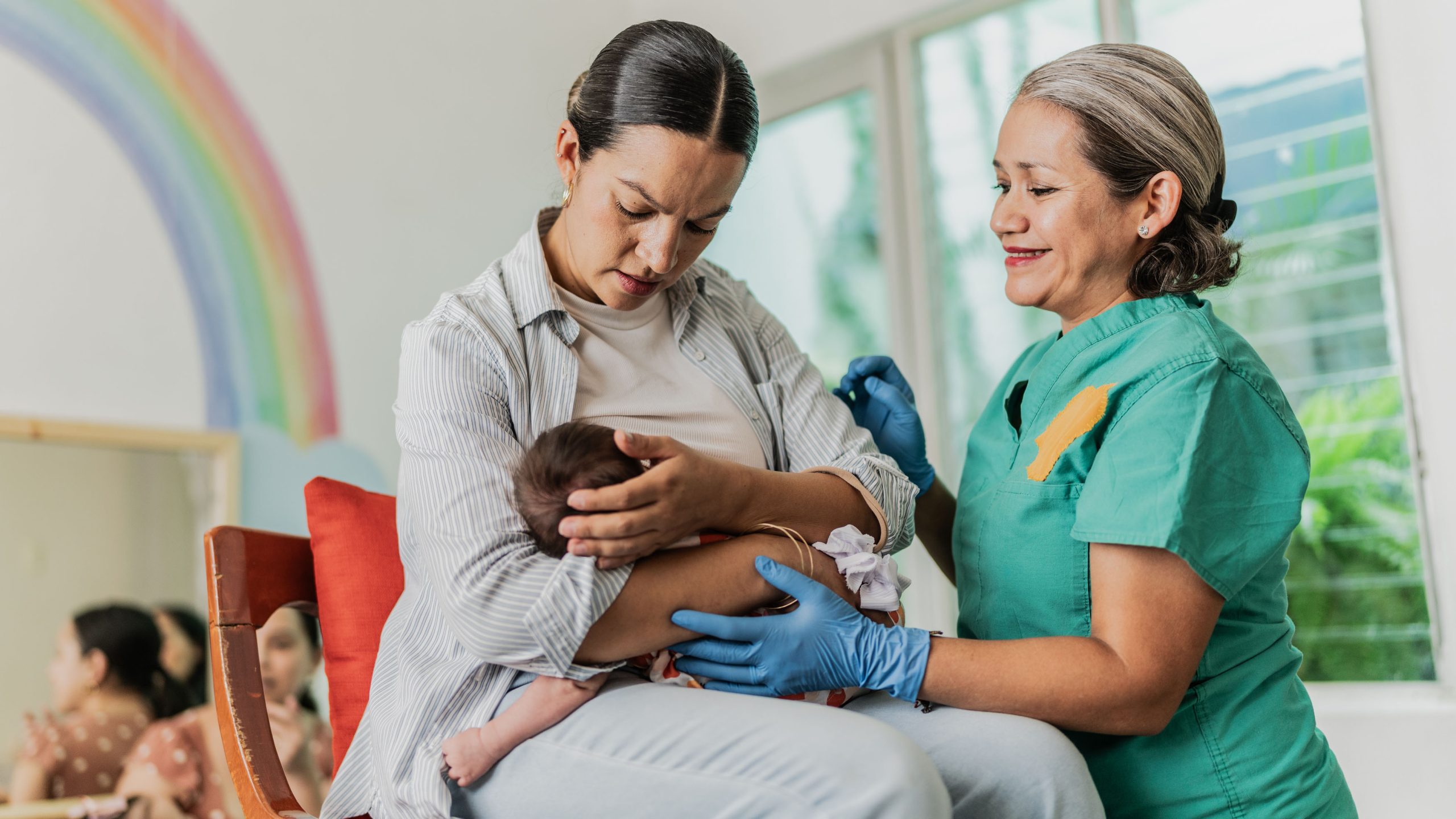 Mom getting breastfeeding support A health care provider helps a new mom with breastfeeding her baby.