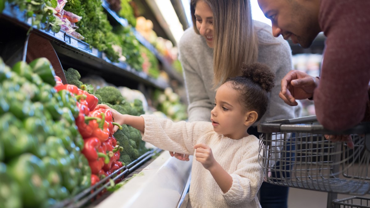 Healthy a mother, father, and child buying fresh vegetables