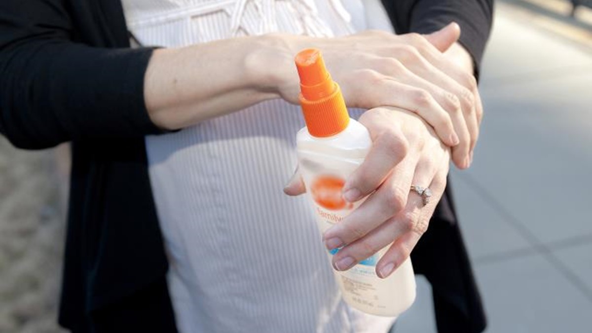 A pregnant woman applying insect repellent.