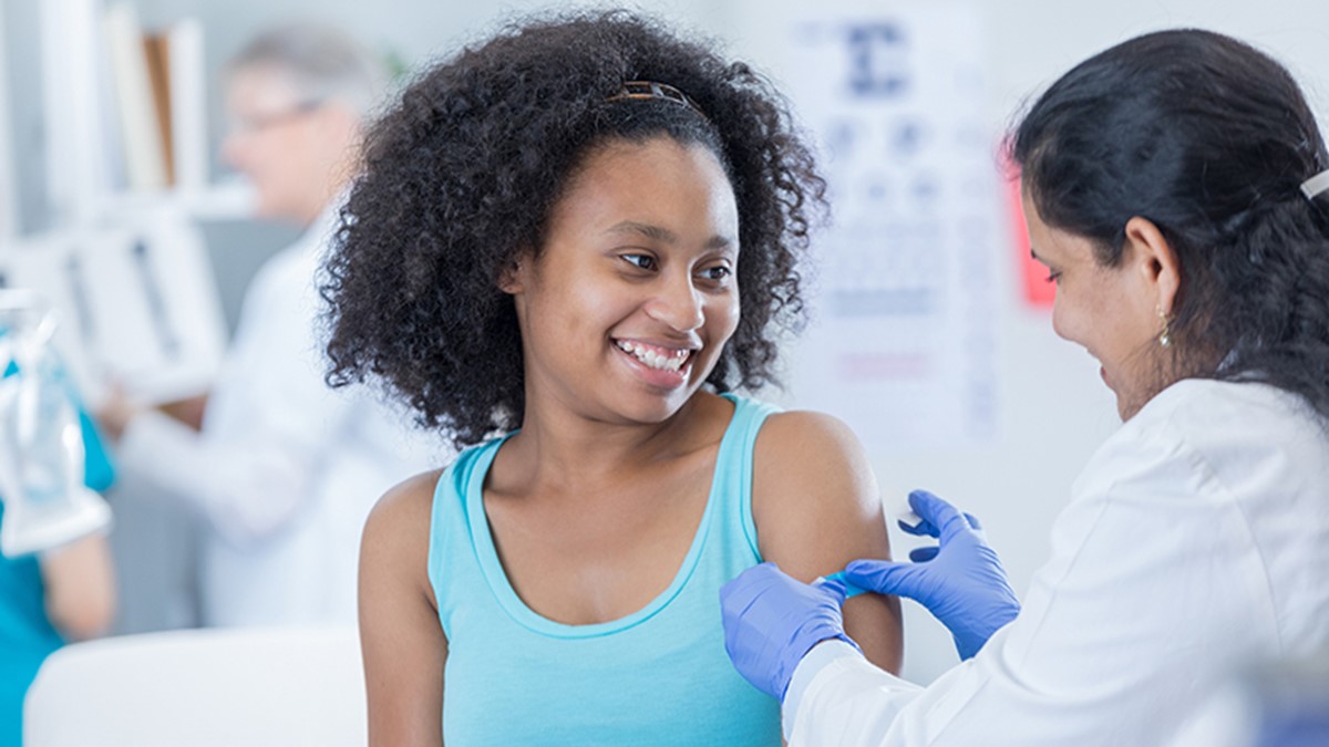Healthcare provider applying a bandage to a pediatric patient's arm.