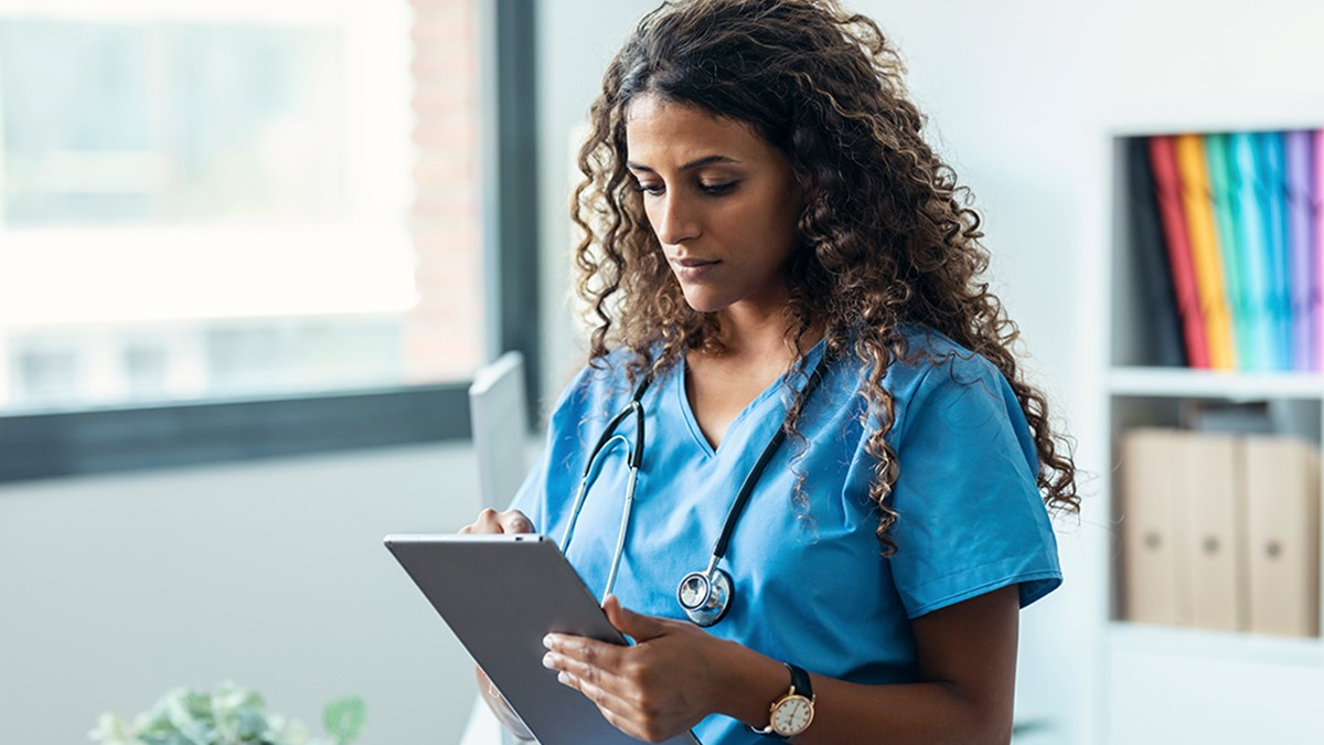 A healthcare provider reading from a tablet in their office.
