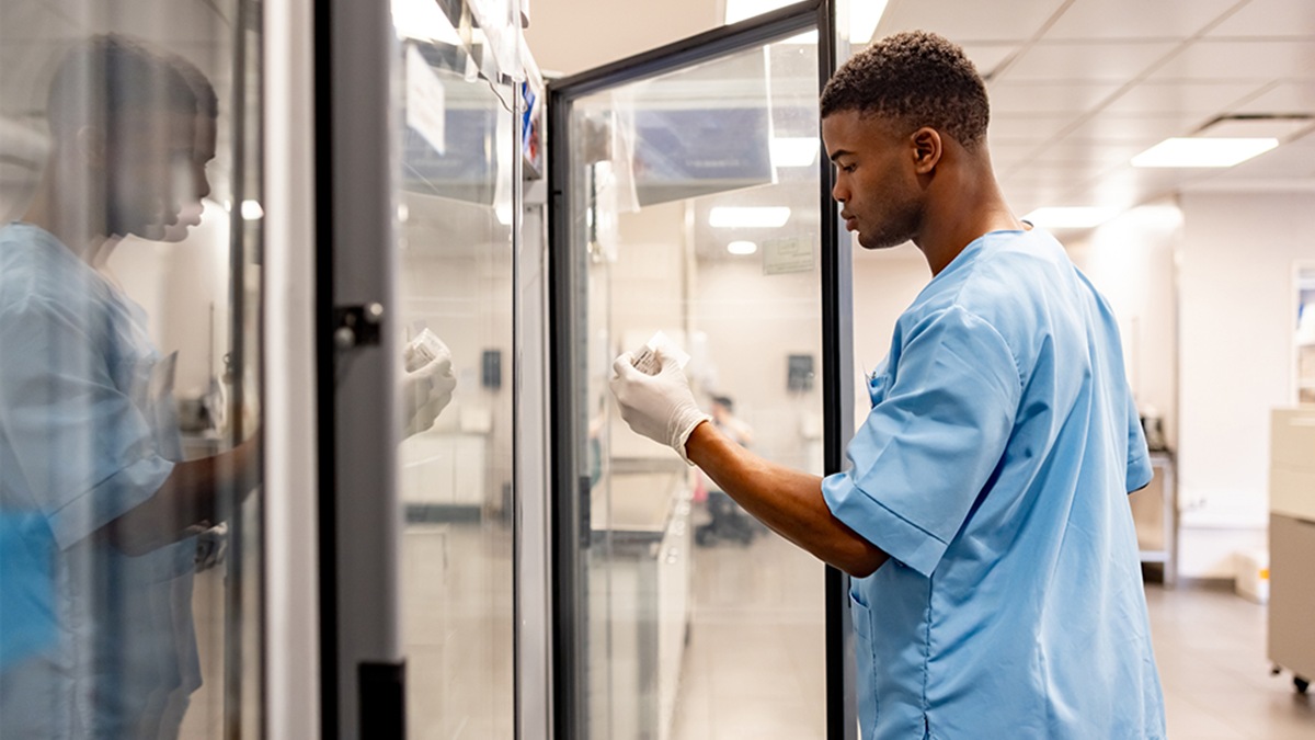 A healthcare provider removing vial from a laboratory refrigerator.