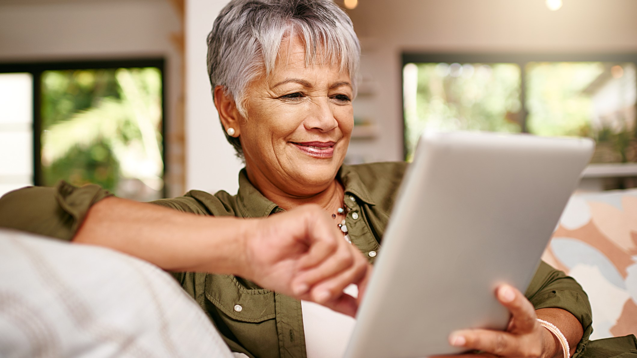 — title missing — Older adult woman smiling and looking at her tablet