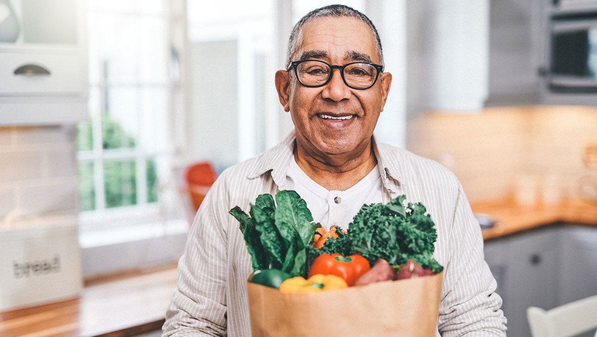 Shot of a elderly man holding a grocery bag in the kitchen Shot of a elderly man holding a grocery bag in the kitchen