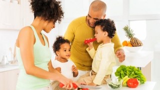 Family meal prep Couple with two children in a kitchen preparing vegetables.
