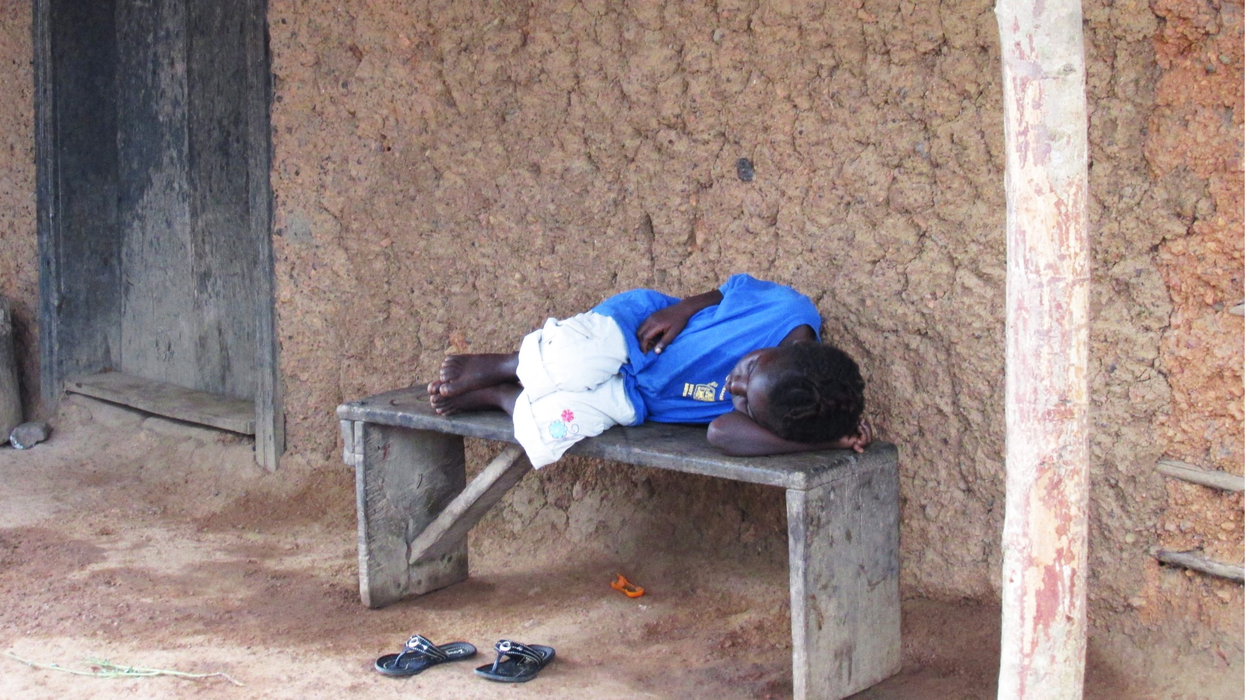 Child waiting for ambulance A sick young girl lies on a wooden bench