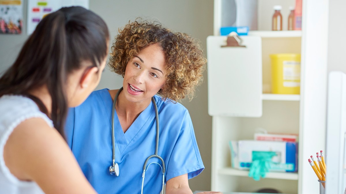 A female healthcare provider talks to a female patient in an office.