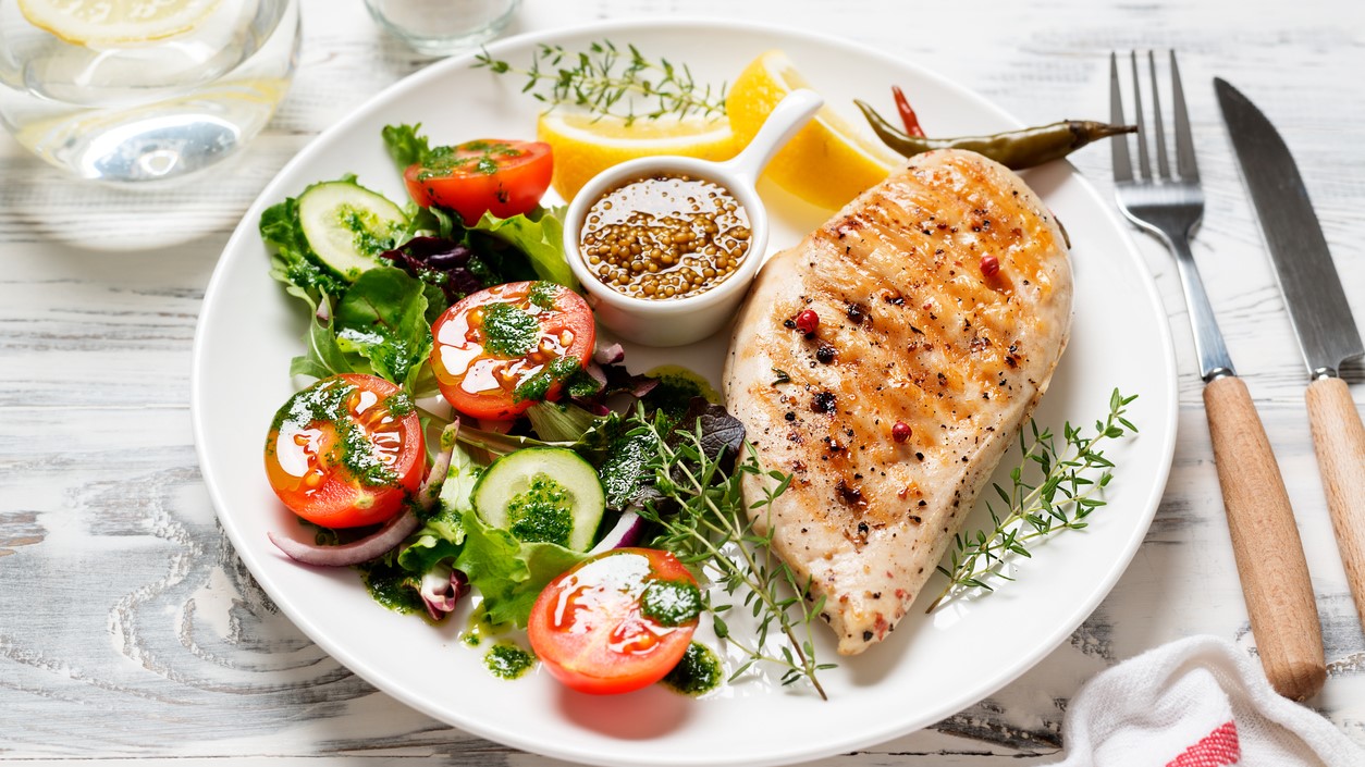 Plate with grilled chicken and fresh green salad
