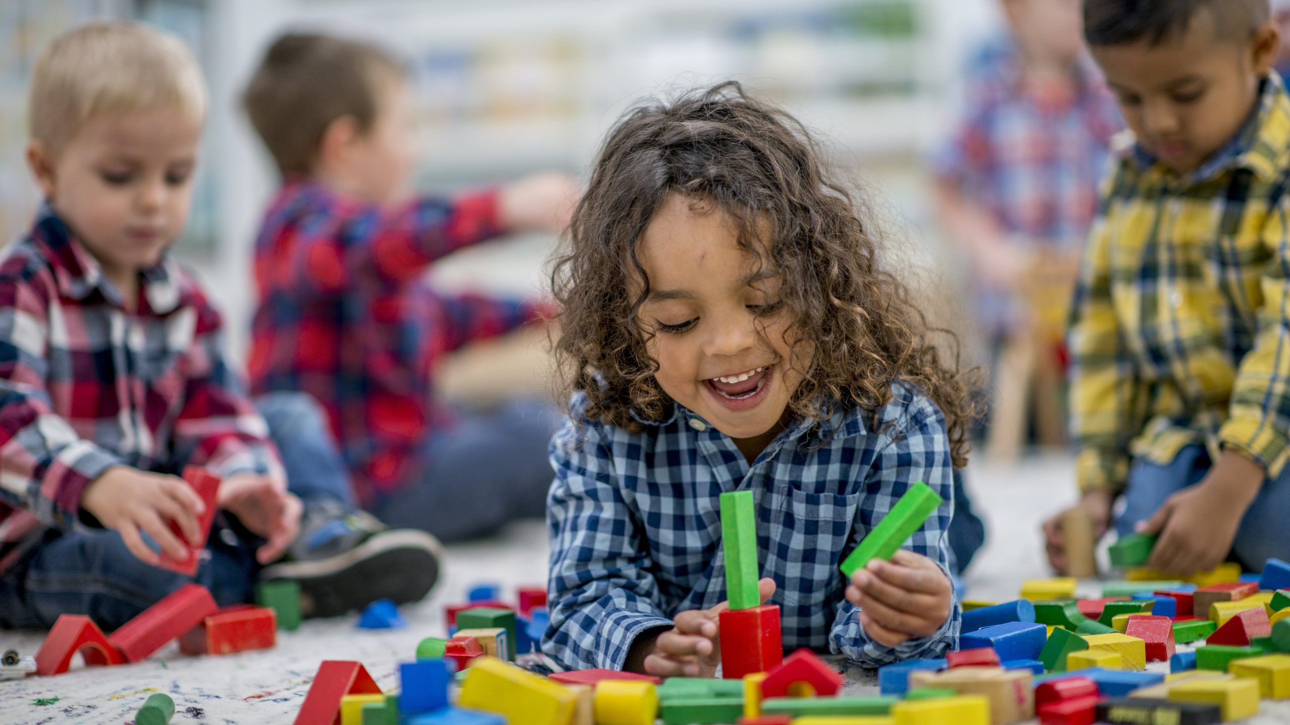 Cinco niños pequeños jugando con bloques y otros juguetes.