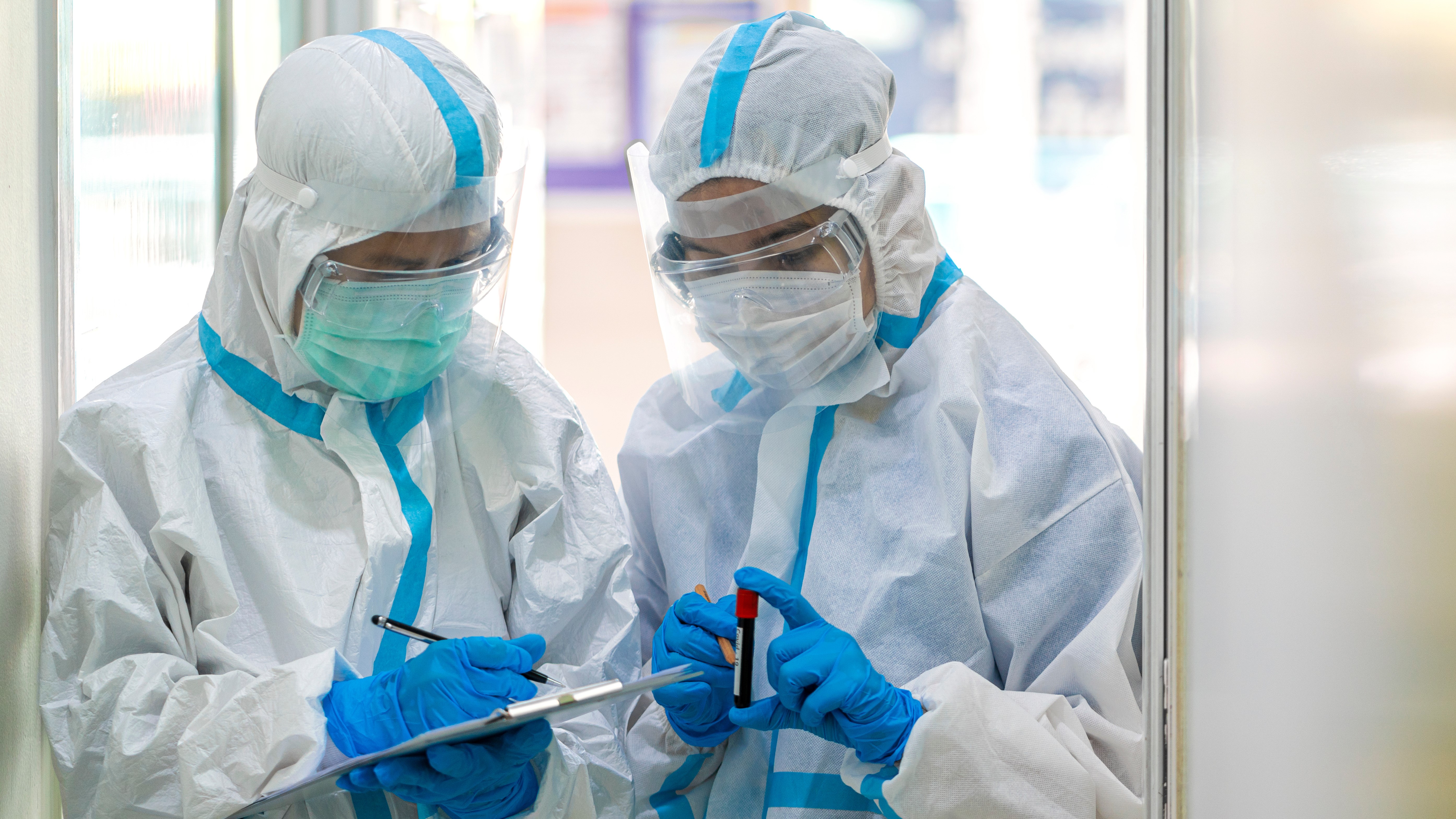 what-we-do-main two people in a lab wearing ppe holding tubes of blood