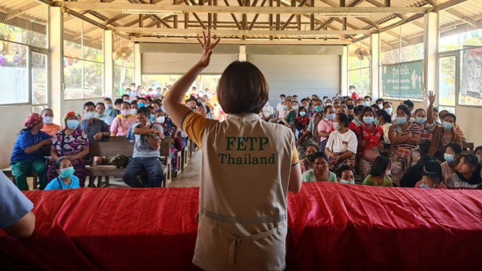 Workforce-core 4 list-first Asian woman in a tan vest hand signaling to an audience.