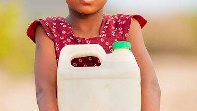 Young girl holding a large plastic jug of water