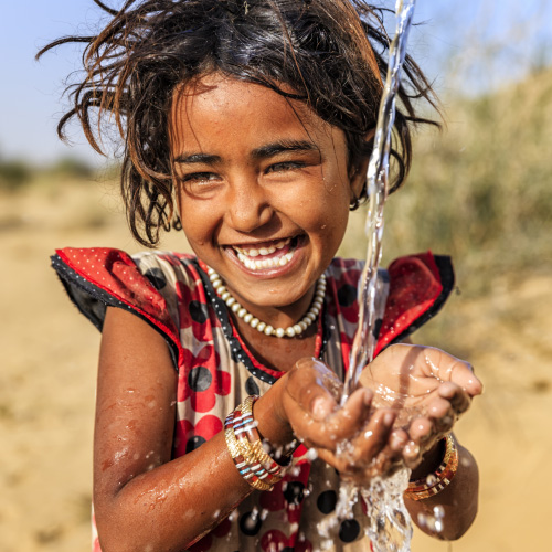 Young girl smiling as water streams through her hands