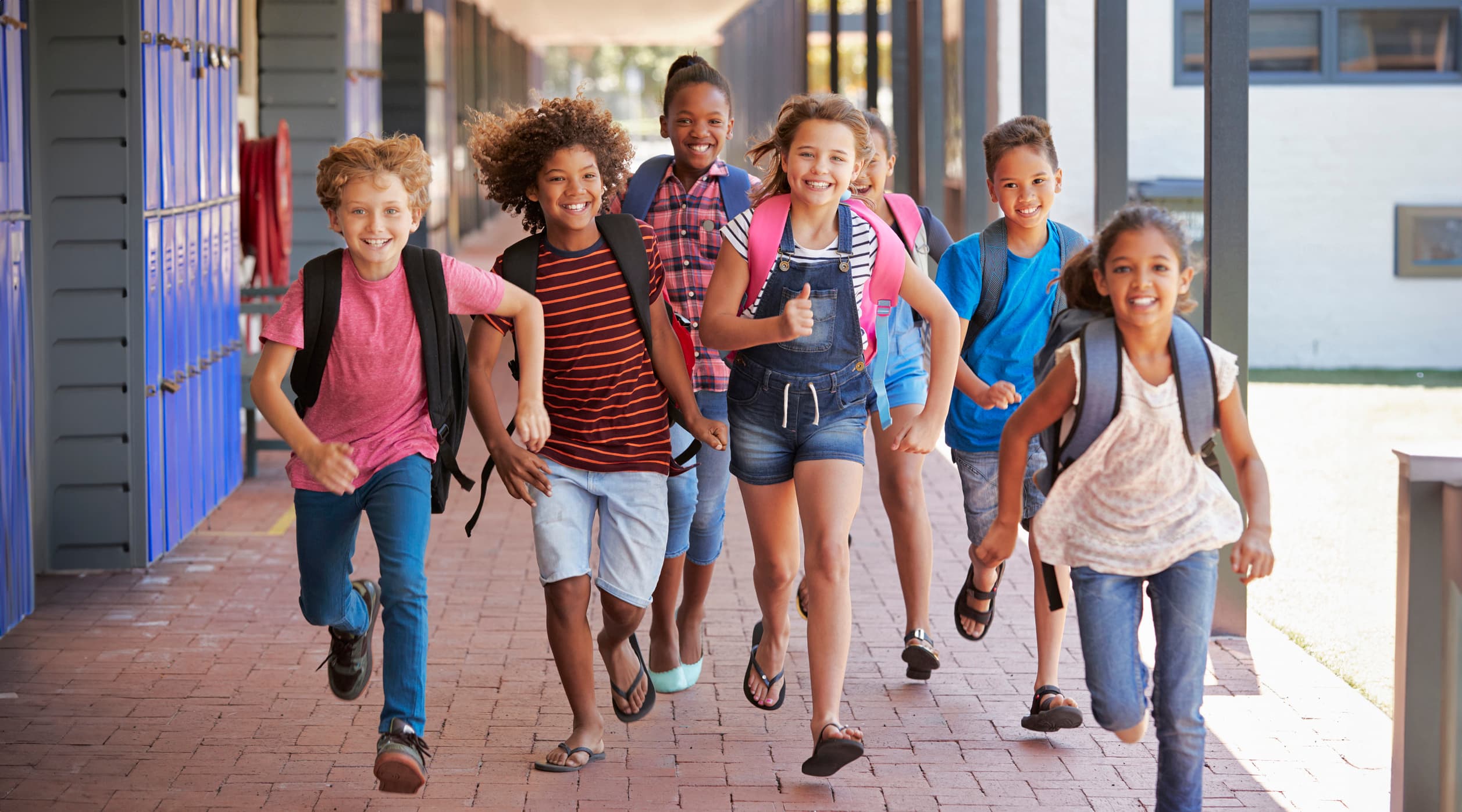 School kids running in elementary school hallway, front view Children running outside of the school.