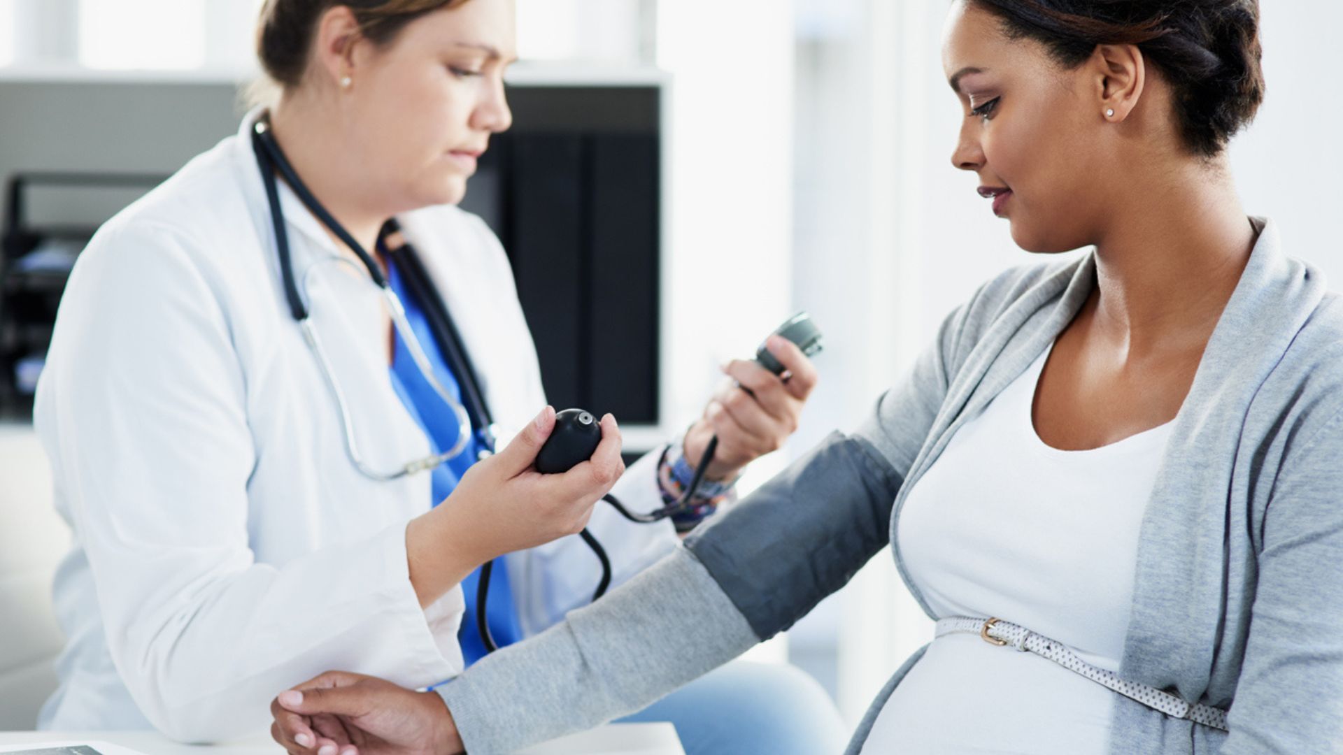Doctor taking pregnant women's blood pressure Doctor taking pregnant women's blood pressure