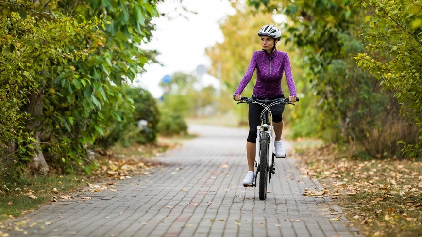 — title missing — Woman riding a bike on a bricked path.