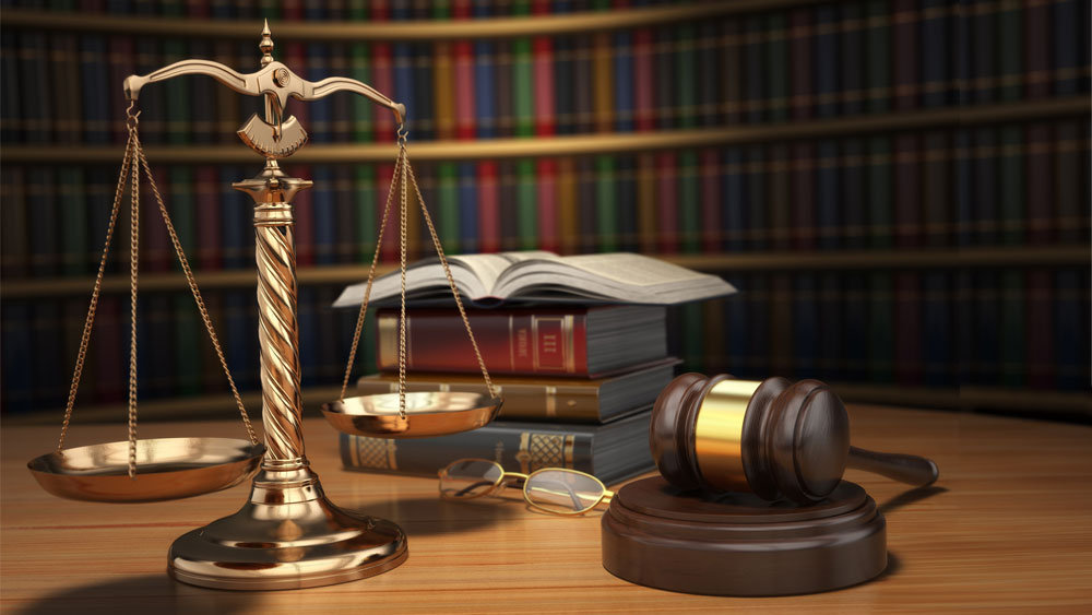 Stack of books Stack of books, gavel, and scales of justice on a table in front of a bookshelf.