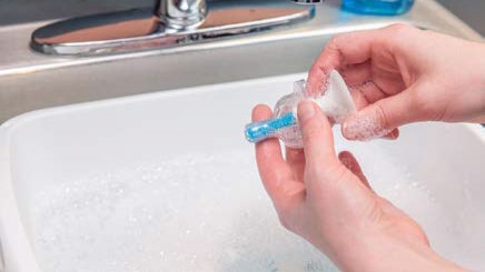 clean-feeding-items-3c A person squeezing soapy water through a bottle nipple.