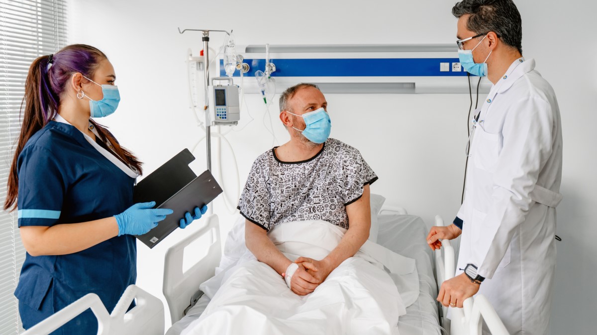 Man Hospital un paciente con cáncer colorrectal en un hospital hablando con su médico y su enfermera