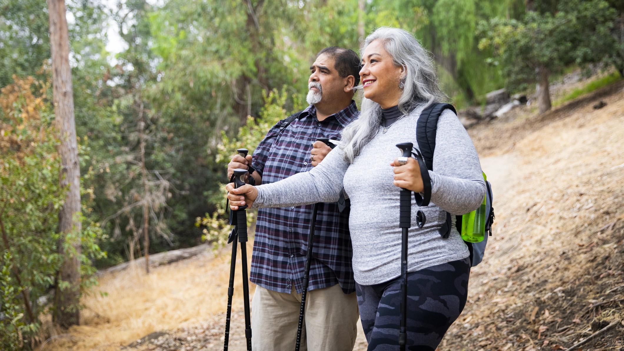 Older couple with backpacks and walking sticks going on a hike.
