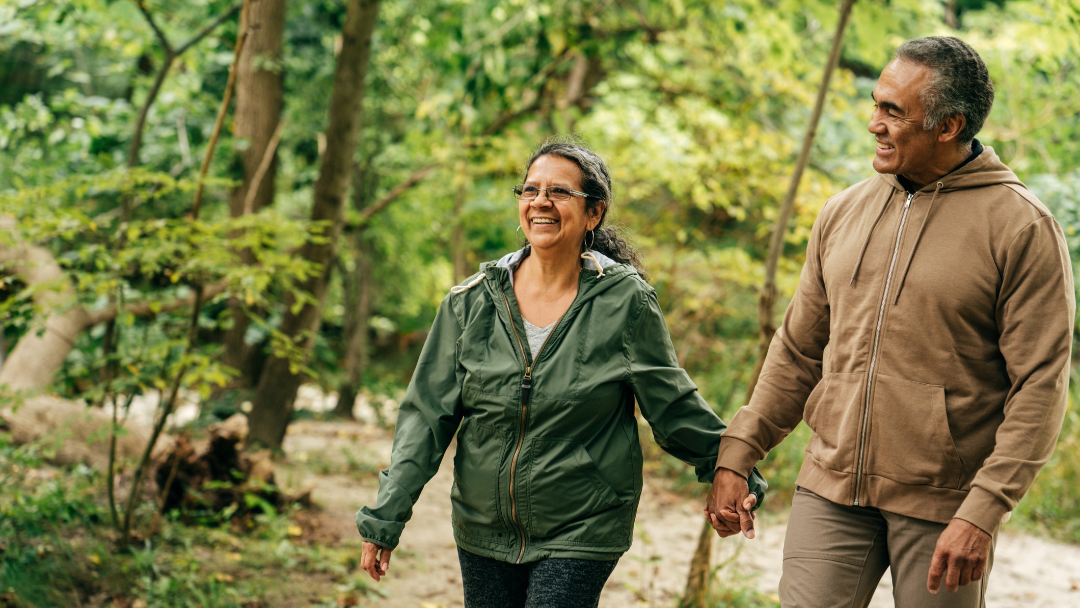 Older couple holding hands and taking a walk outside.