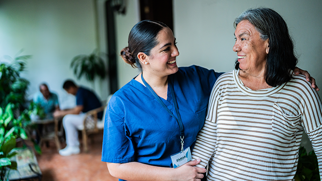 Personal care aide smiling and assisting an older female patient