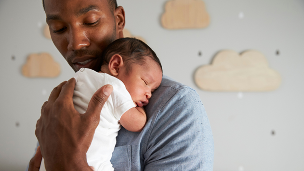 Parent holding baby A parent holding their infant against their chest.
