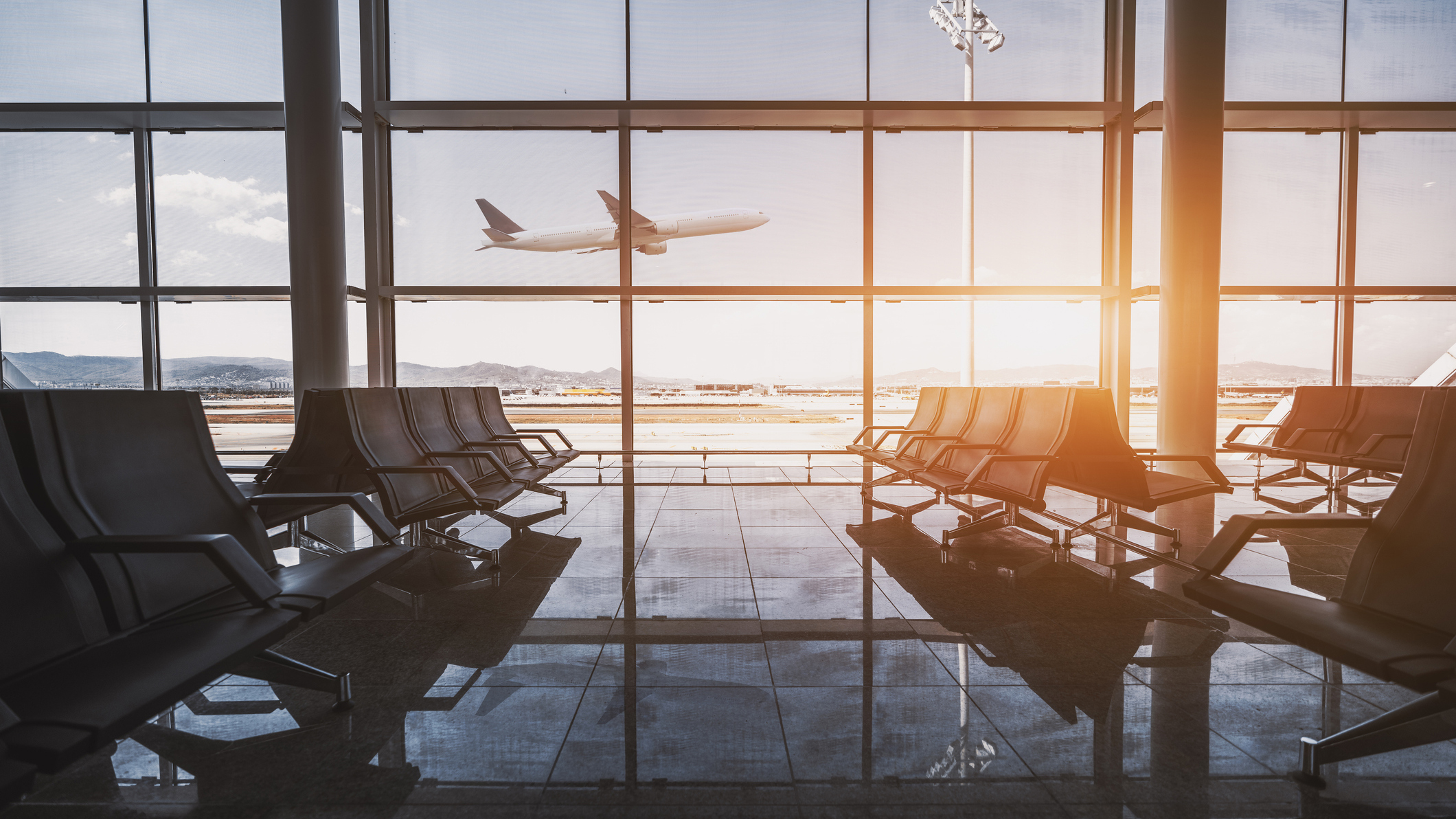 A commercial aircraft taking off viewed through the windows of an airport.