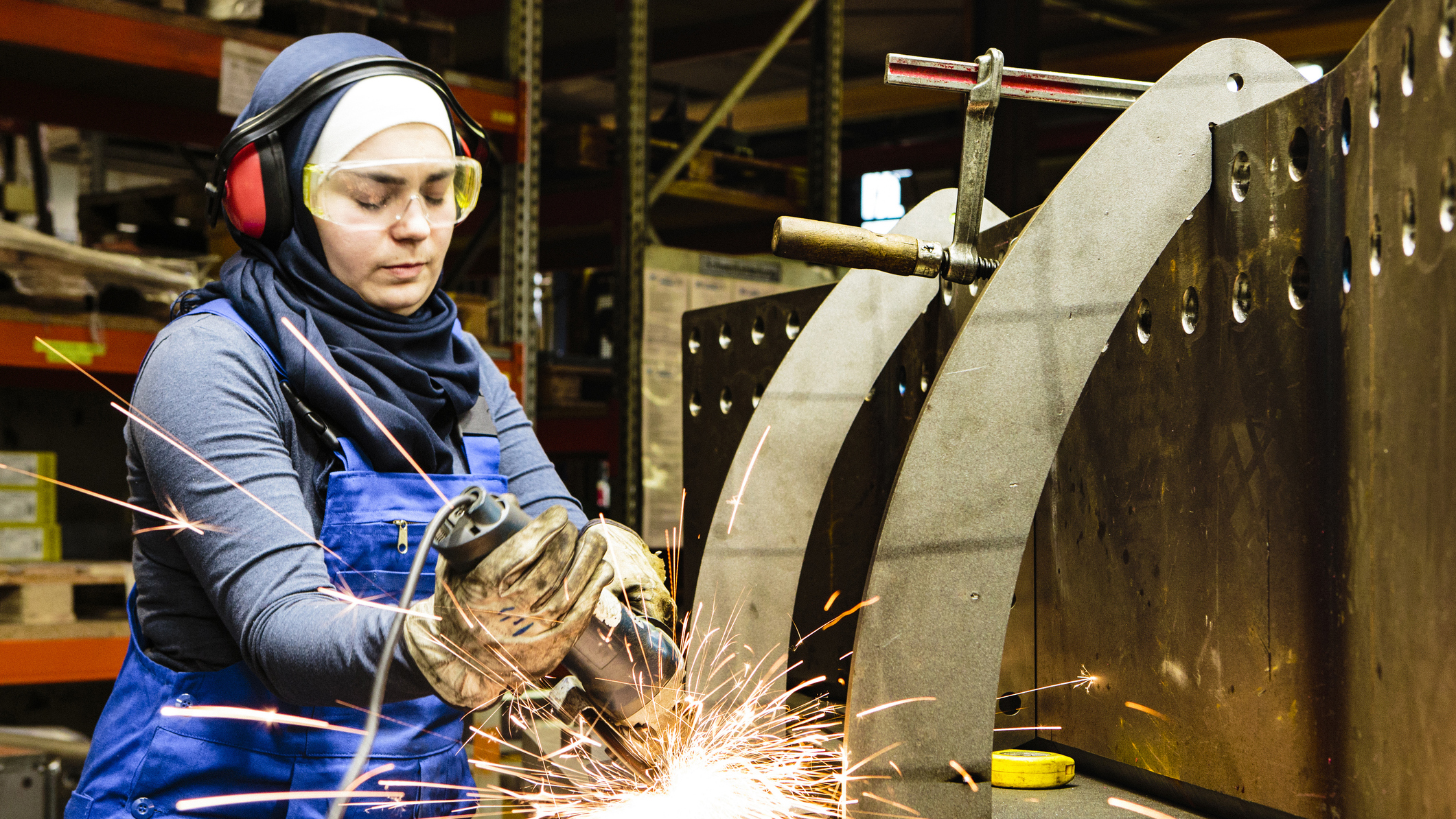 A female worker in PPE is shown working in an industrial setting.