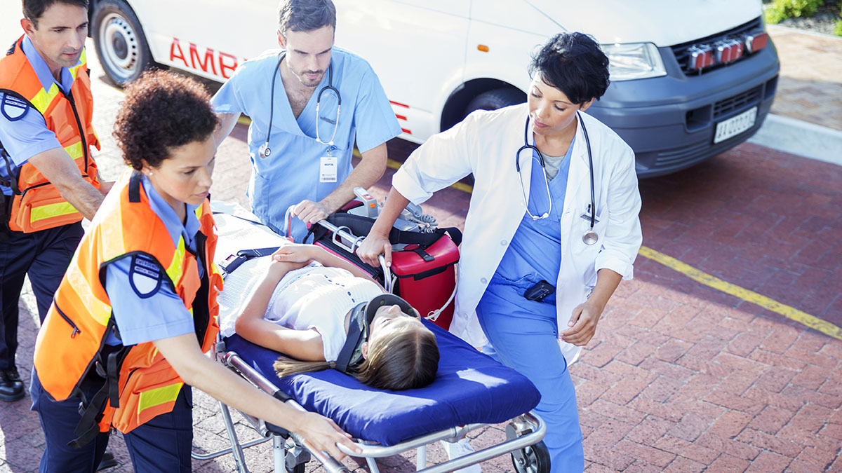 Doctor, nurse and paramedics wheeling patient on stretcher