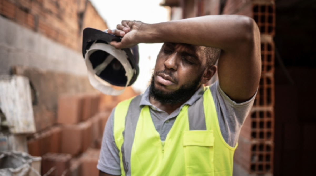 — title missing — Worker wiping brow, showing signs of exhaustion.