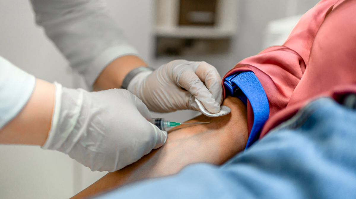 — title missing — Gloved hands drawing blood from patient's arm.