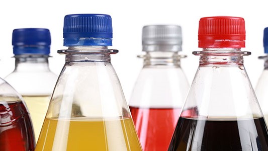 — title missing — Image of the tops of bottles with sugary drinks.