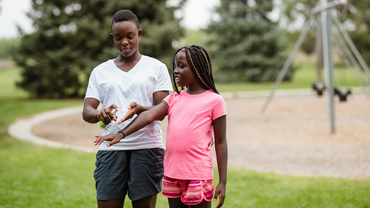 Apply insect repellent Photo showing an adult applying insect repellent to a child's arm.