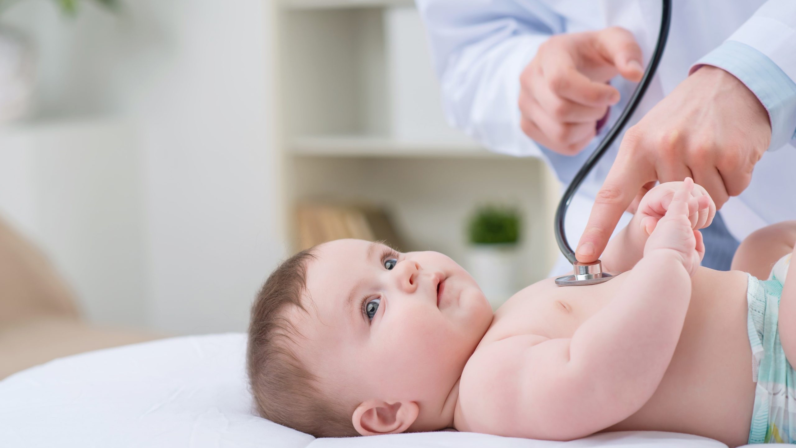 Un médico usa un estetoscopio para escuchar los pulmones de un bebé.