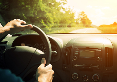 Man driving a car on a country road in bright sunshine