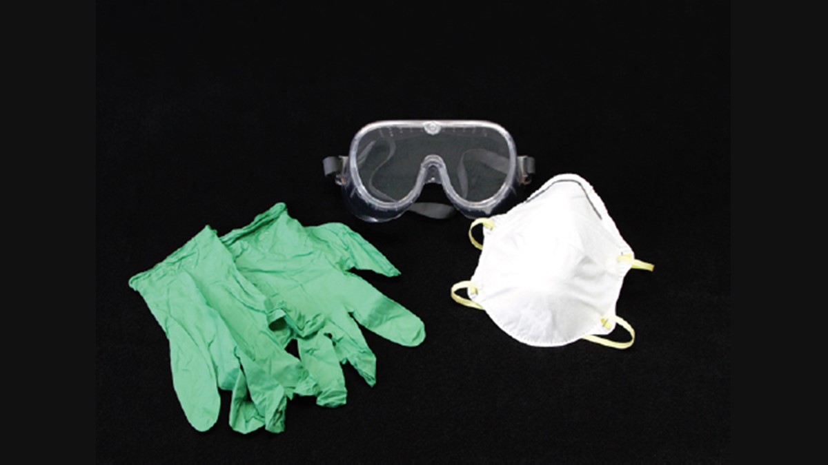 A pair of safety goggles, a dust mask, and a pair of rubber gloves on a black background.