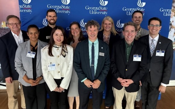 Ten persons pose in front of a Georgia State University backdrop