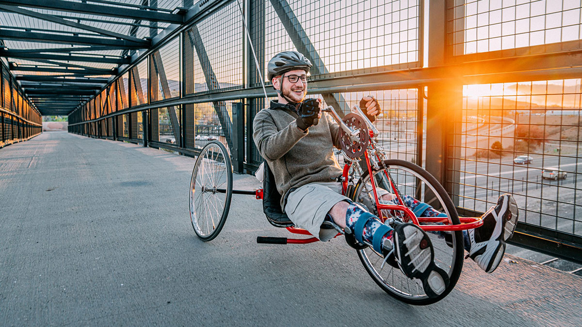 Adult riding an adaptive bike over a bridge
