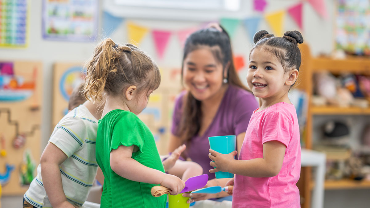 Un proveedor de cuidado temprano que trabaja con niños en la mesa de actividades